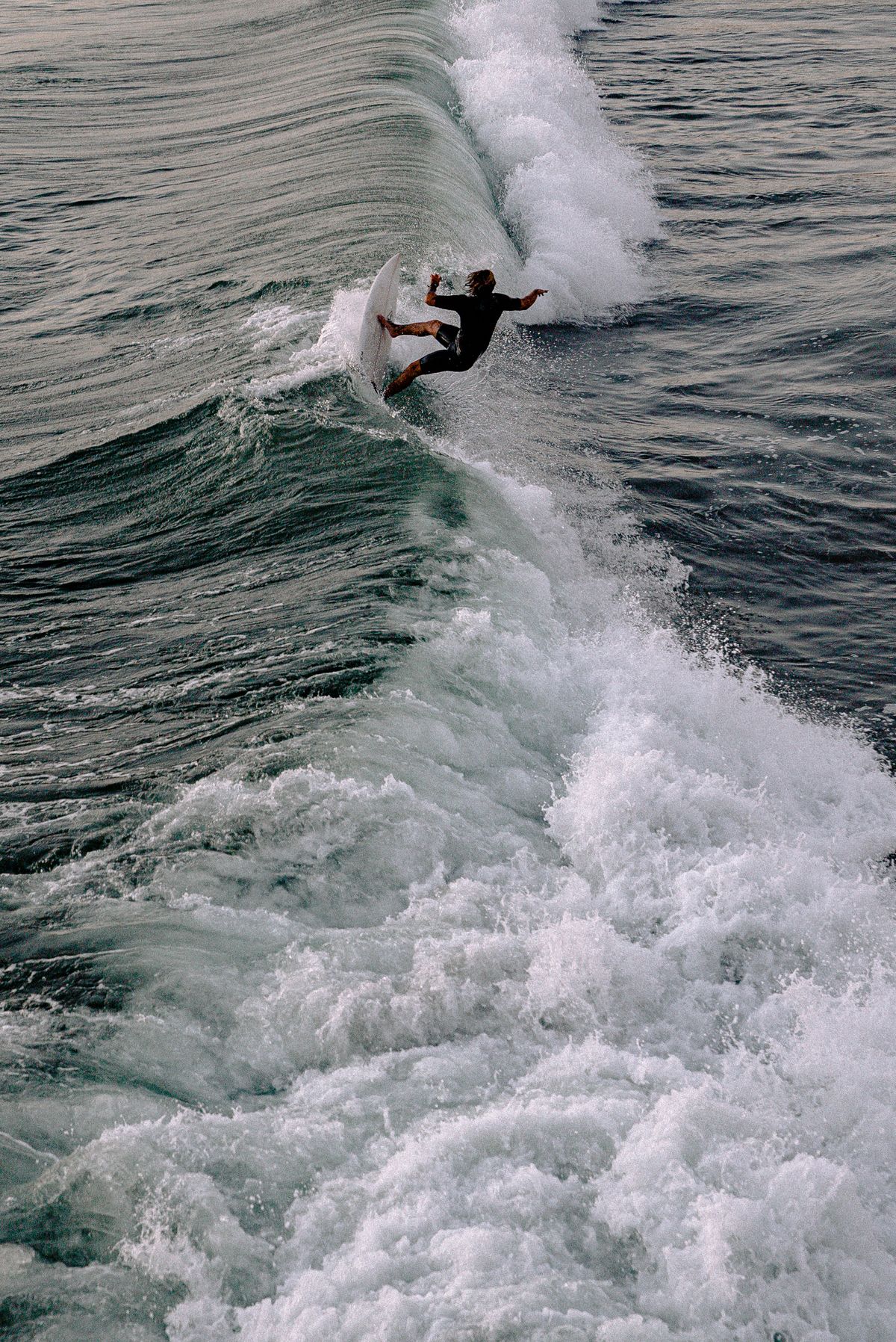 Beginner surfer standing up on a small wave in a low, balanced stance