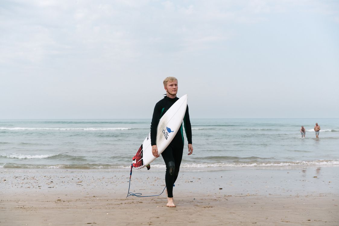 Beginner surfer carrying a board on the beach