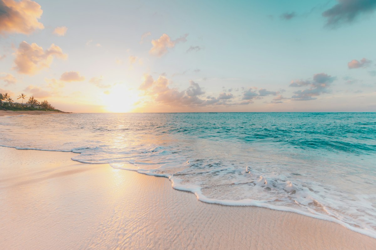 Clean ocean waves rolling onto a sandy beach at golden hour