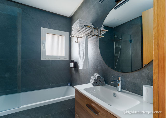 Bathroom on the upper floor of the BigBlue Bay Duplex with a bath, slate walls and a round mirror