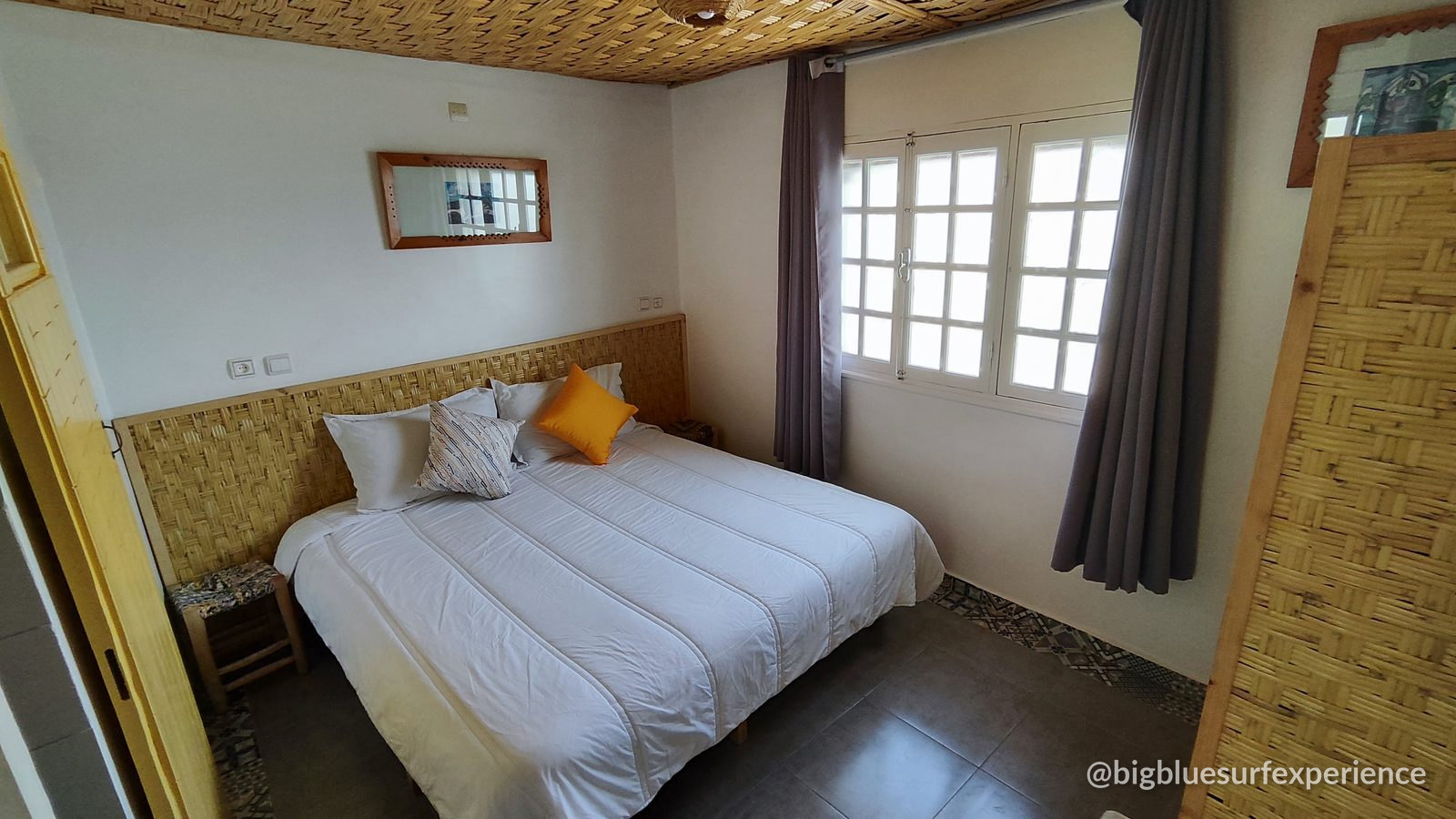 Double room at BigBlue Surf Hostel with bamboo headboard and a large window
