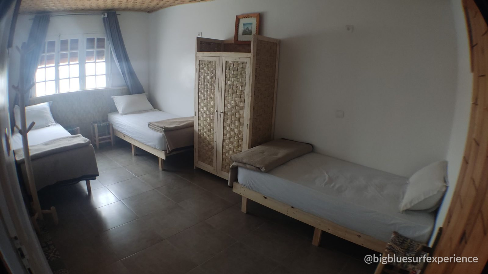 Triple room at BigBlue Surf Hostel with three single beds and a wardrobe